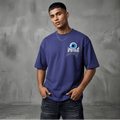 Man wearing a blue t-shirt with a logo against a gray textured wall