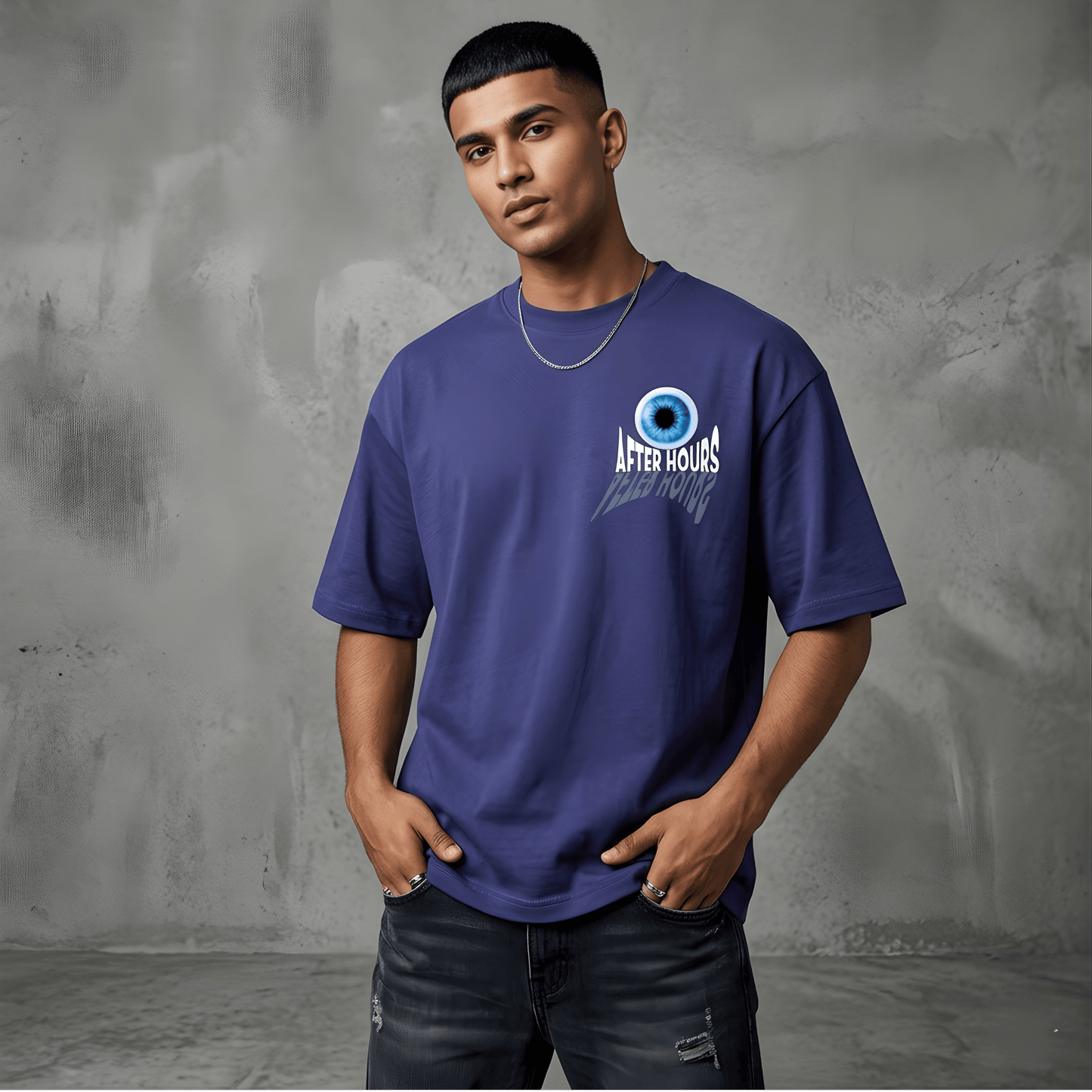 Man wearing a blue t-shirt with a logo against a gray textured wall