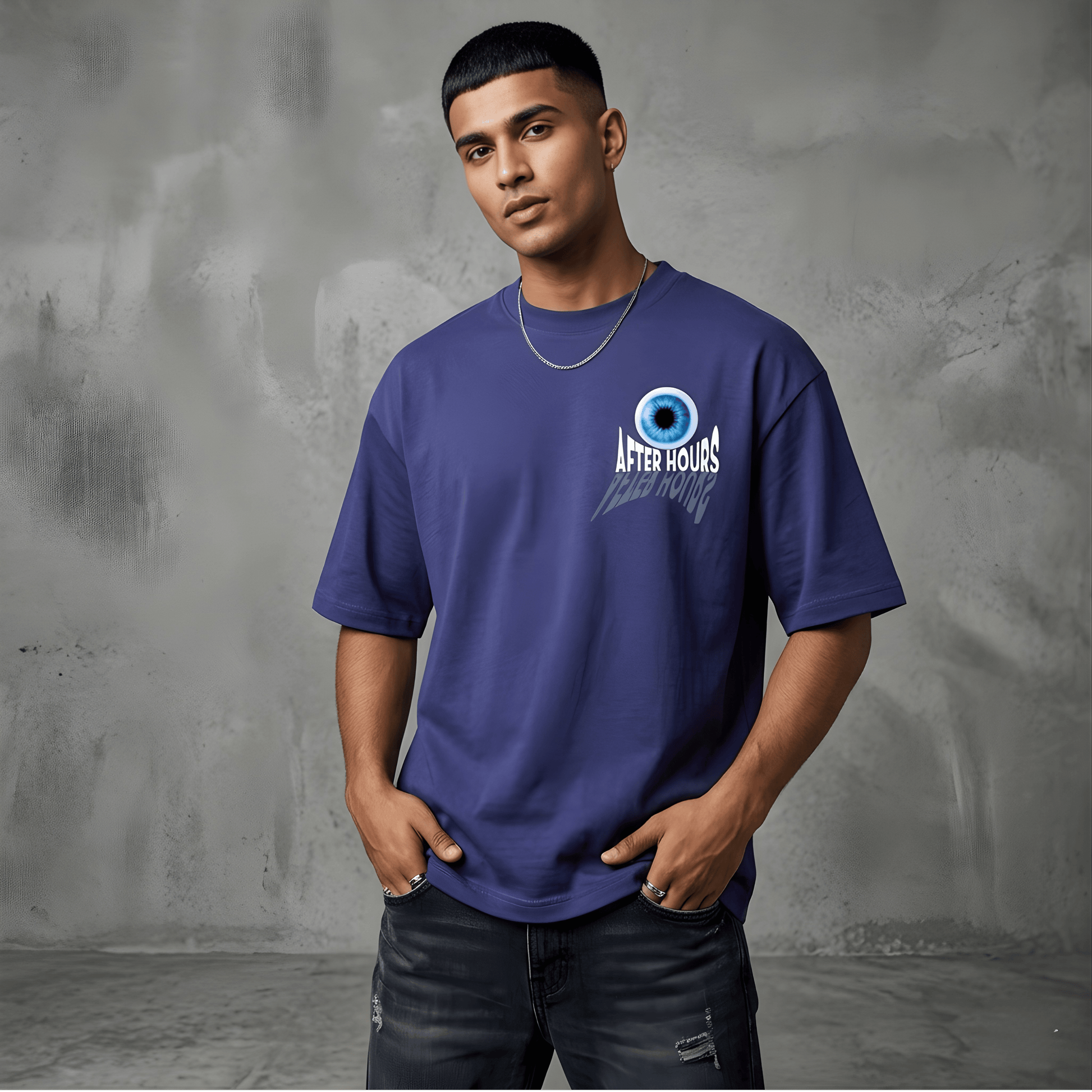 Man wearing a blue t-shirt with a logo against a gray textured wall