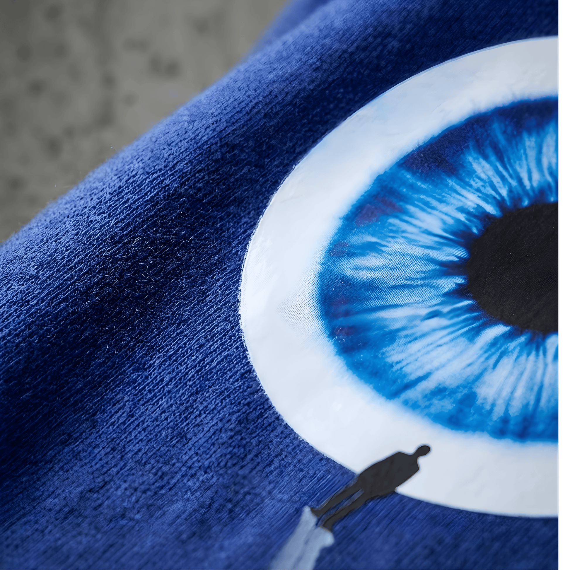 Close-up of a blue eye design on a dark fabric background