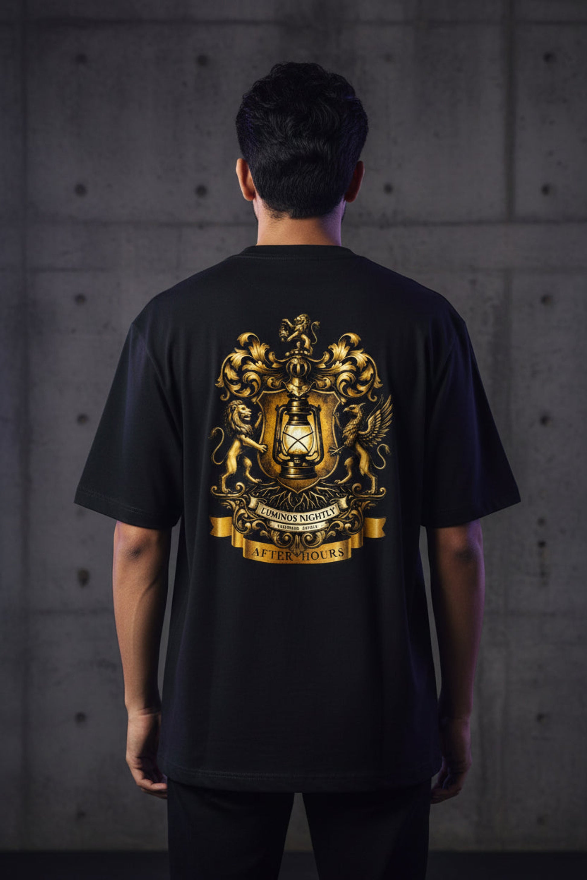Black t-shirt with gold After Hours Coat of Arms emblem on the back against a grey background