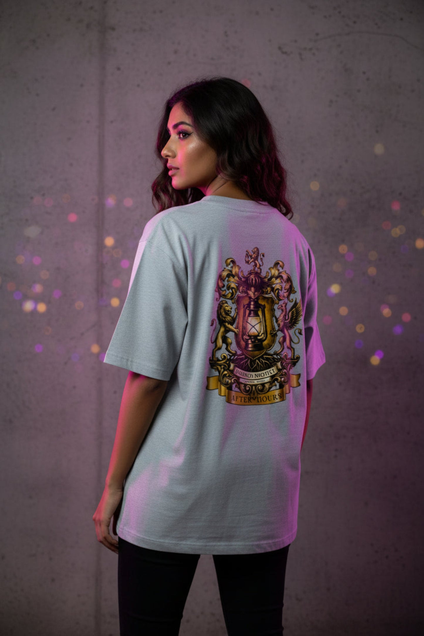 Grey t-shirt with a gold After Hours Coat of Arms emblem on the back against a grey background