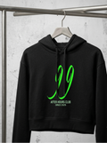 A black cropped hoodie hanging on a wooden hanger from a metal clothing rack, featuring a bright green graphic of the number '99' and the text 'AFTER HOURS CLUB' and 'SINCE 2025' on the front.