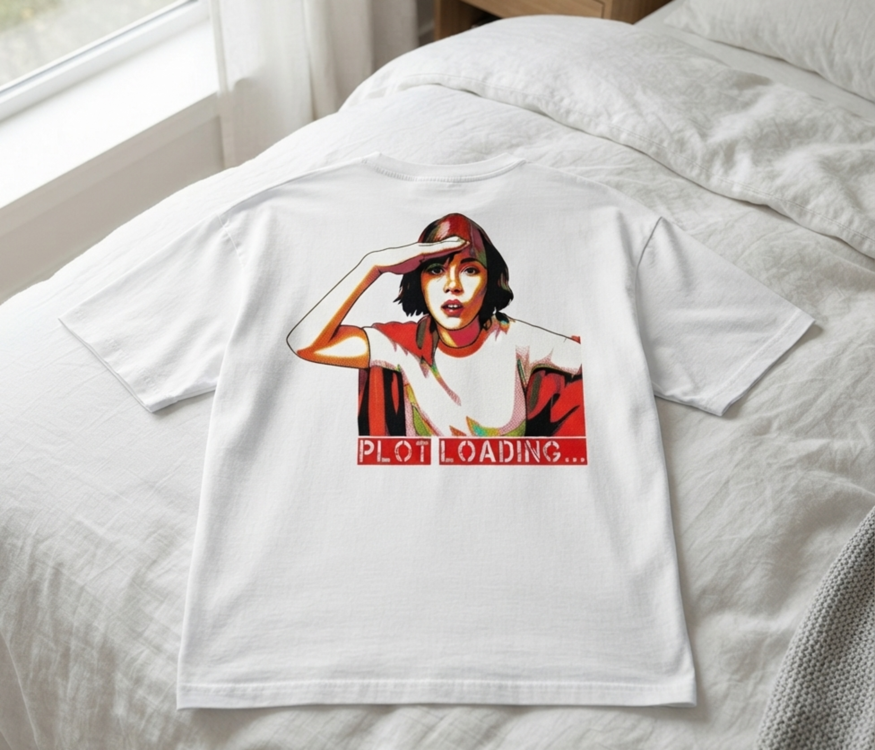 A white short-sleeve T-shirt laid flat on a bed, featuring a graphic print of a woman in a red headscarf with the text 'PLOT LOADING.