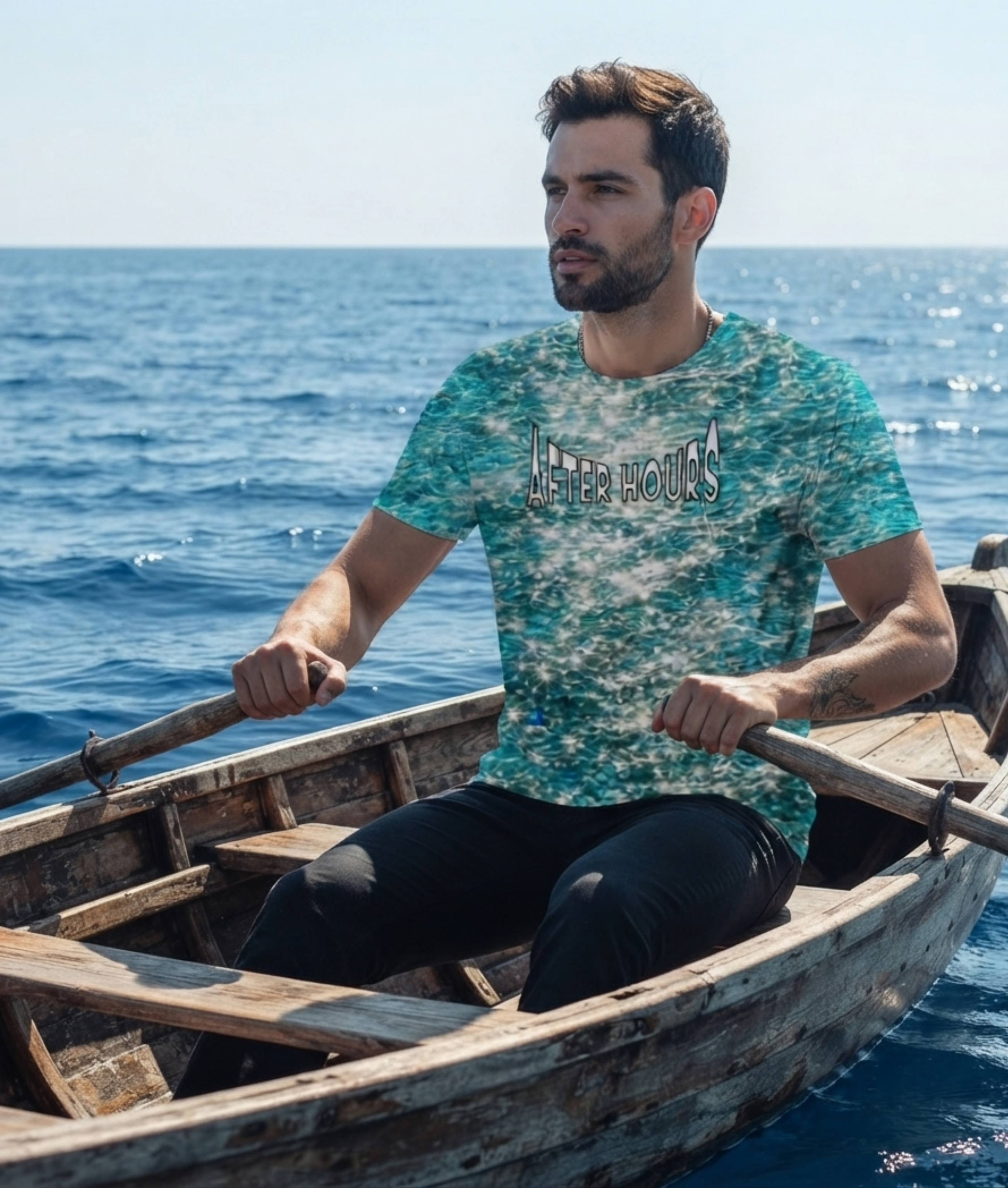 A man sitting in a wooden rowboat on the ocean wearing a blue and white patterned t-shirt with 'AFTER HOURS' printed across the chest, paired with black pants.