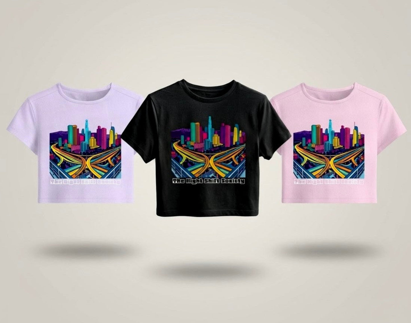 Three t-shirts with colourful cityscape designs on a light grey background