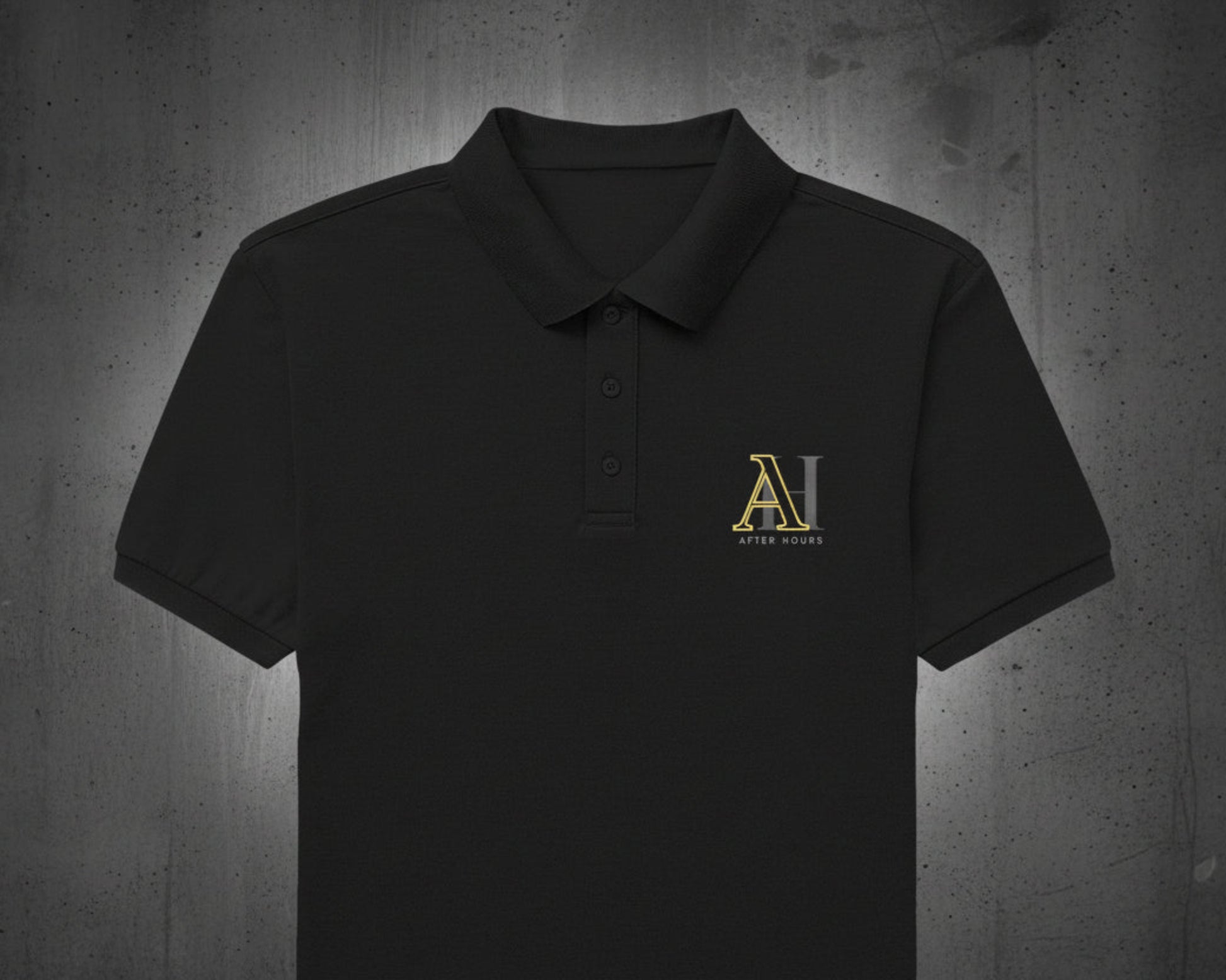 Black polo shirt with gold logo on a grey textured wall background