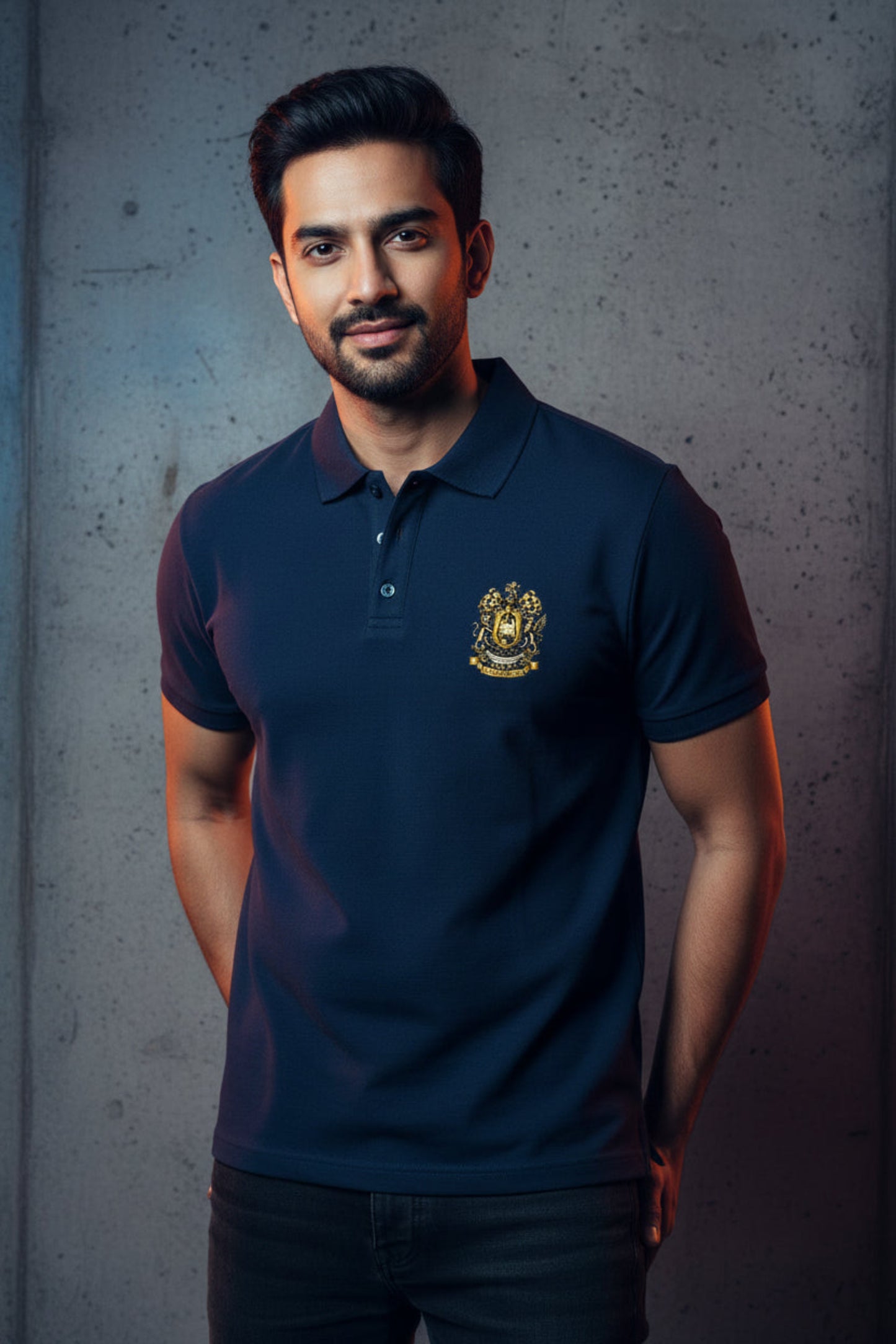 Navy blue polo shirt with the After Hours Coat of Arms emblem on a grey textured wall background