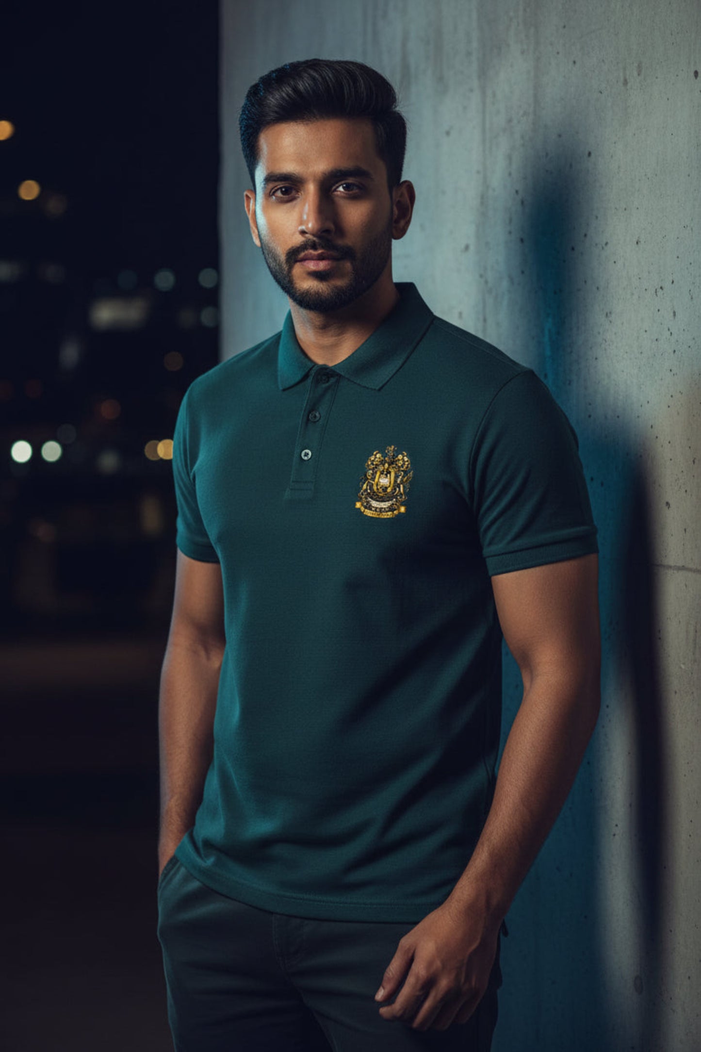 Petrol blue polo shirt with the After Hours Coat of Arms emblem on a grey background