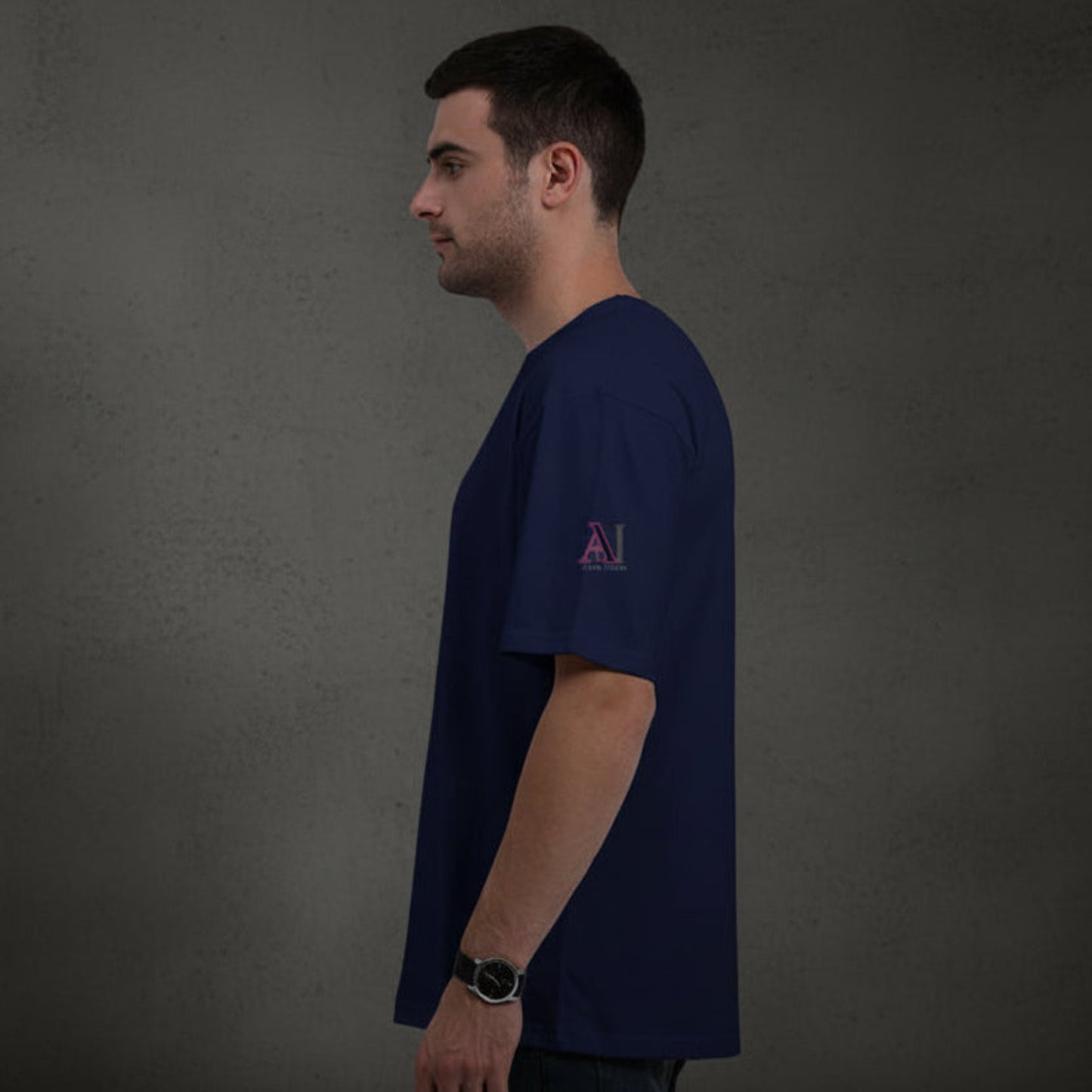 Man wearing a blue t-shirt with a logo on a grey textured wall background