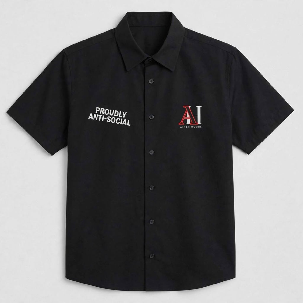 A black short-sleeve button-up shirt with 'PROUDLY ANTI-SOCIAL' printed in white on the right chest and a red and white 'AH' logo on the left chest, displayed on a light gray background.