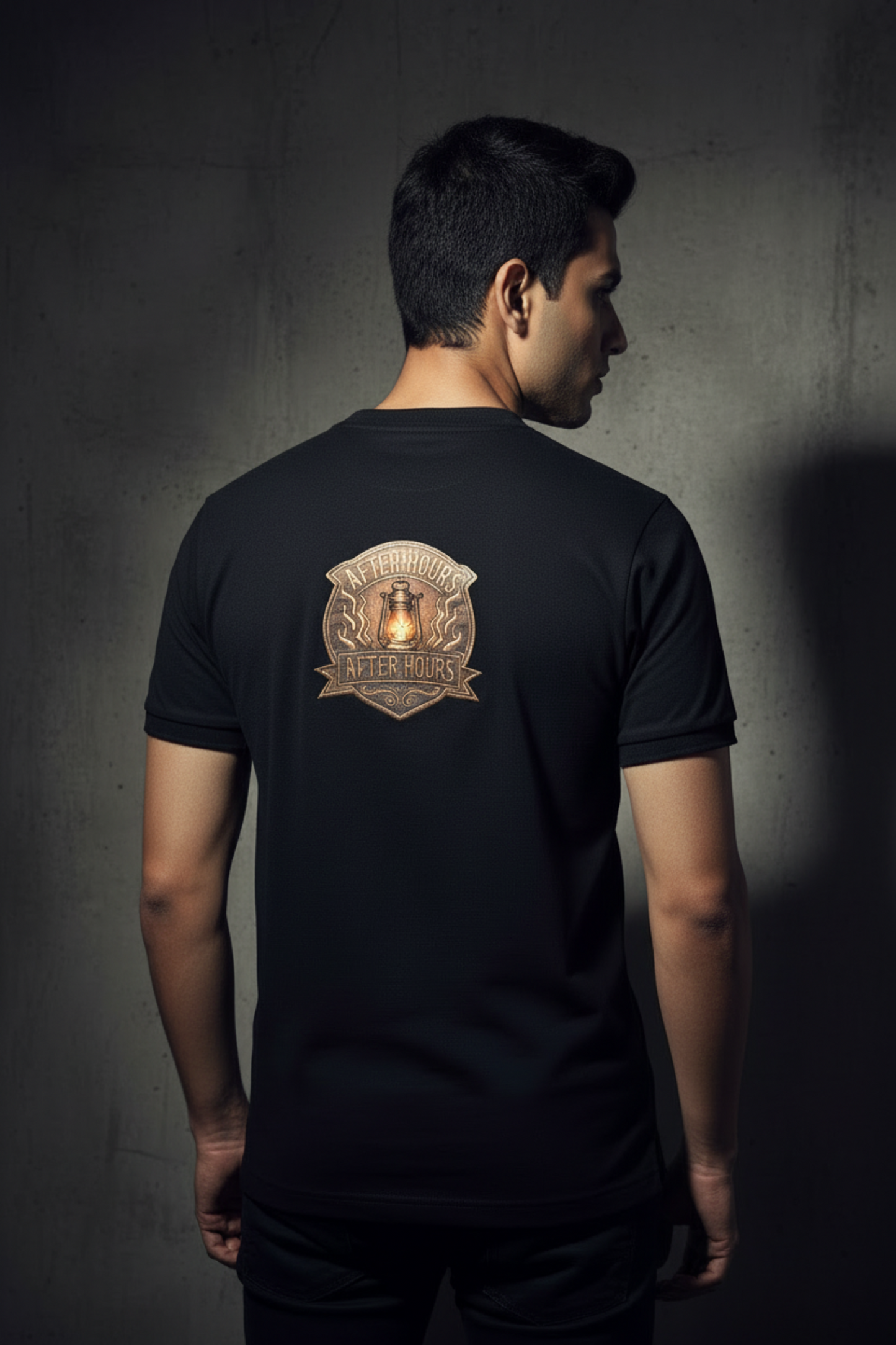 Black t-shirt with a logo on the back against a grey textured wall background