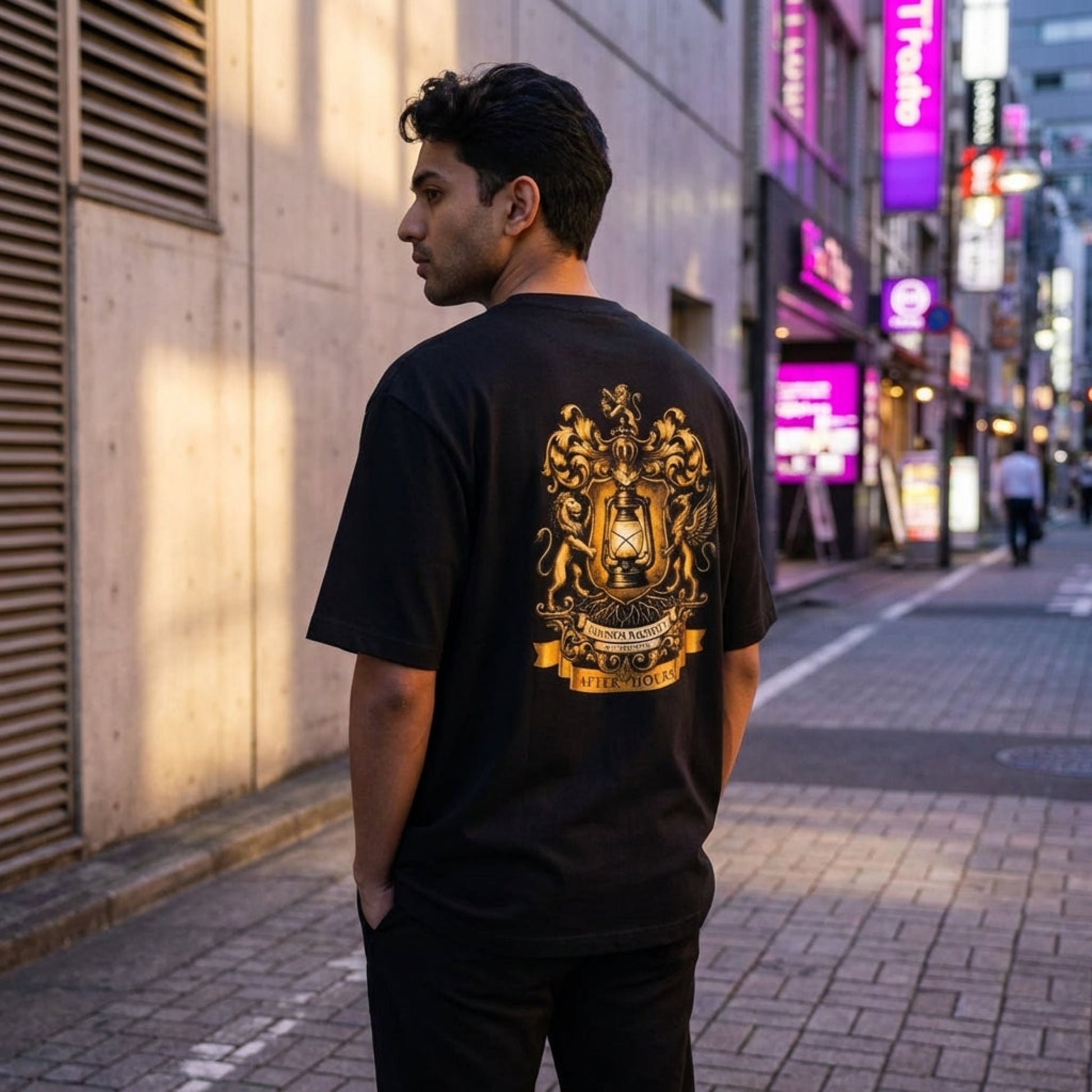 Full-body view of model wearing oversized tee in urban dusk setting, showcasing relaxed silhouette and large back crest graphic.