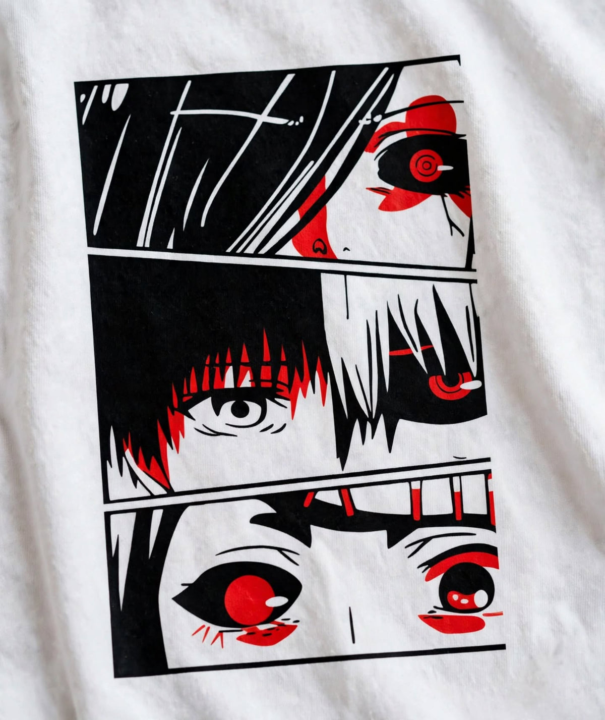 A close-up of a white fabric garment featuring a large rectangular anime-style graphic print in black, white, and red, showing stylized eyes and hair details.
