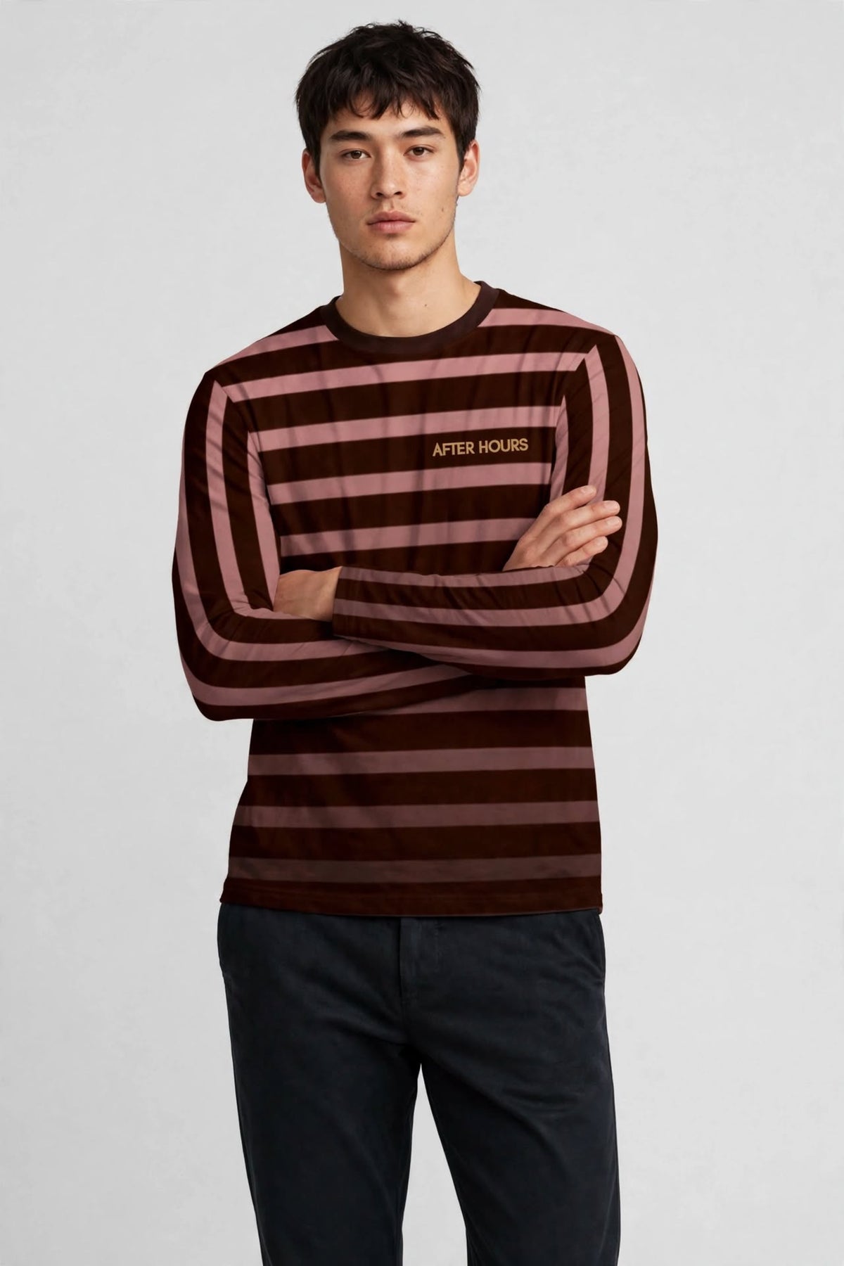 A man wearing a long-sleeve striped shirt with dark brown and dusty rose horizontal stripes, featuring a small gold 'AFTER HOURS' logo on the chest, paired with dark pants, against a light grey background.