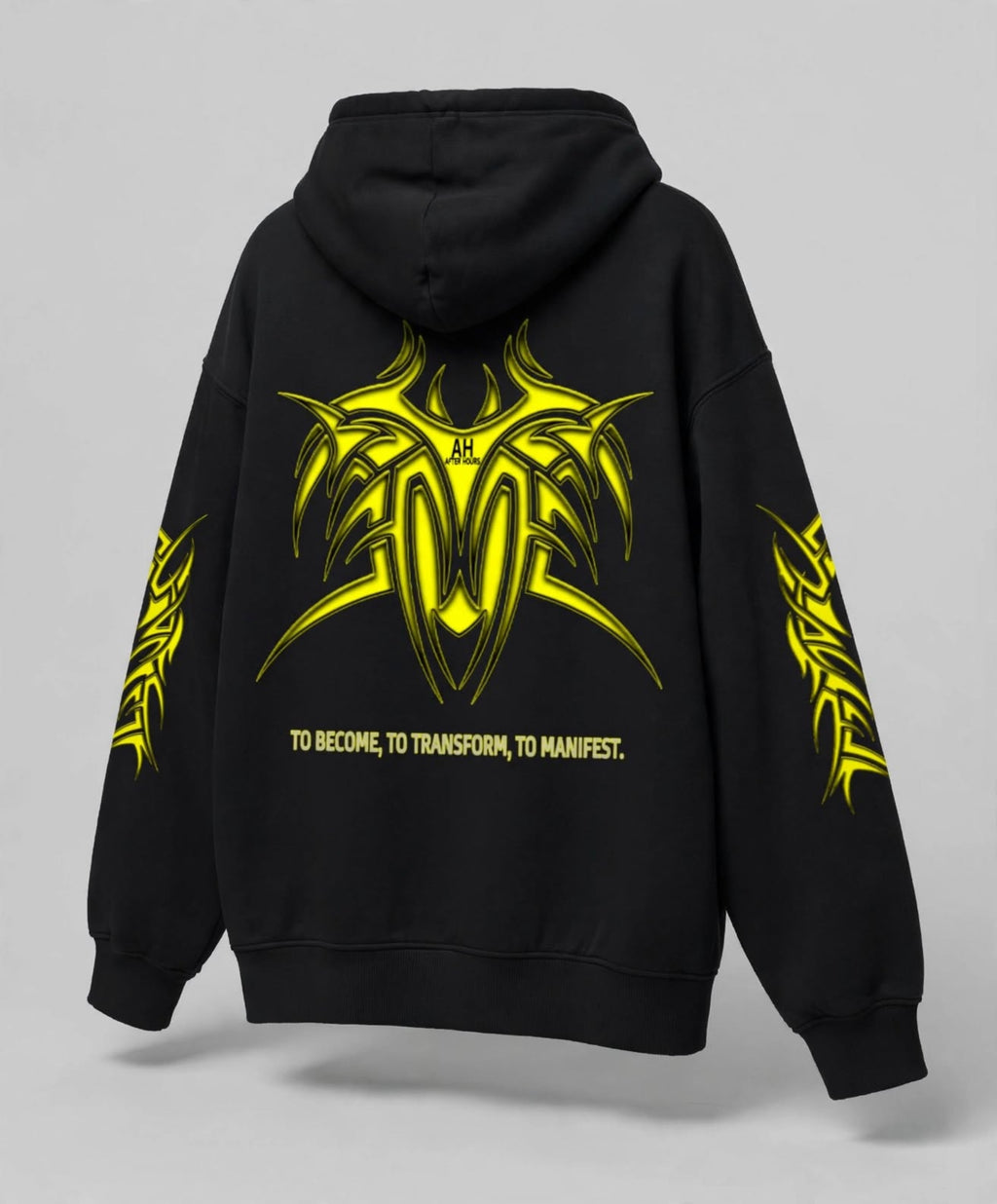 Black pullover hoodie shown from the back, featuring a large neon yellow tribal-style graphic with the text 'TO BECOME, TO TRANSFORM, TO MANIFEST.' across the lower back and matching yellow graphics on both sleeves.