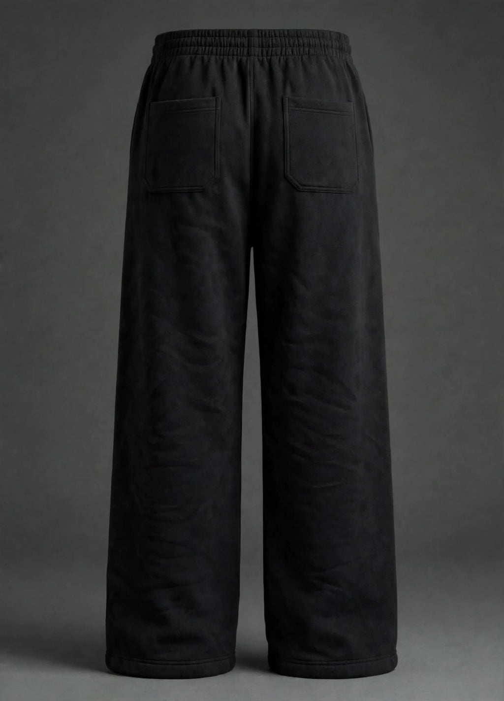 Black wide-leg sweatpants shown from the back, featuring an elastic waistband and two large patch pockets, photographed against a dark grey studio background.