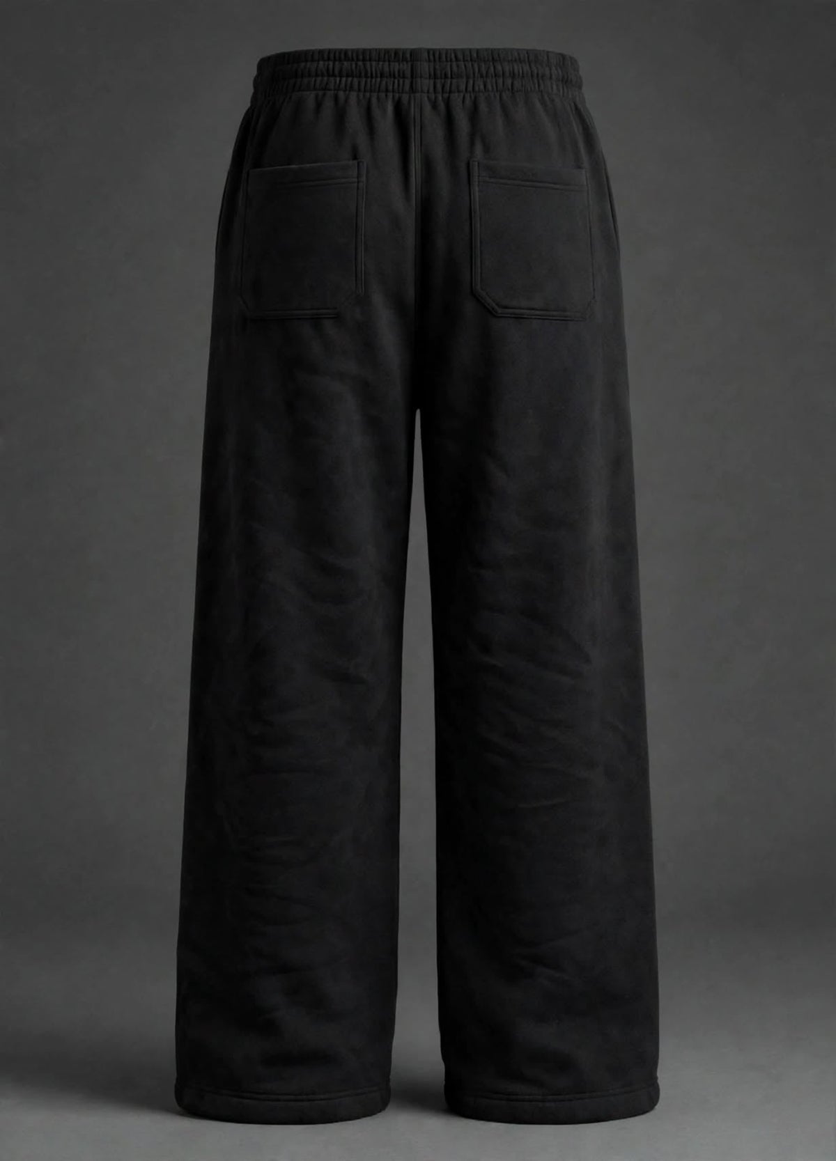 Black wide-leg sweatpants shown from the back, featuring an elastic waistband and two large patch pockets, photographed against a dark grey studio background.