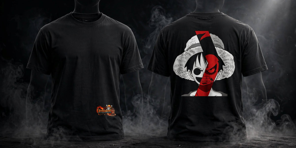 Two black short-sleeve t-shirts shown from the front and back against a dark smoky background. The front shirt has a small orange and white graphic near the lower left hem, and the back shirt features a large graphic of a straw-hat character with red and black details.