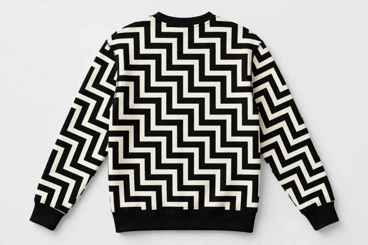 A long-sleeve crewneck sweatshirt featuring a bold black and off-white zigzag optical illusion pattern, shown flat against a light grey background.