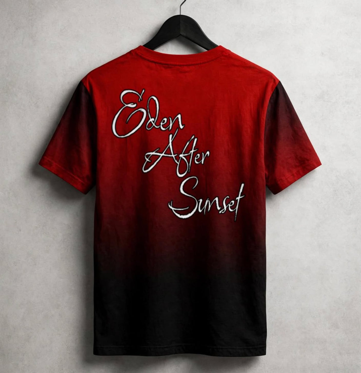 A short-sleeve t-shirt with a red-to-black gradient design, hanging on a black hanger against a textured grey wall. The back of the shirt features the phrase 'Eden After Sunset' in a white cursive font.