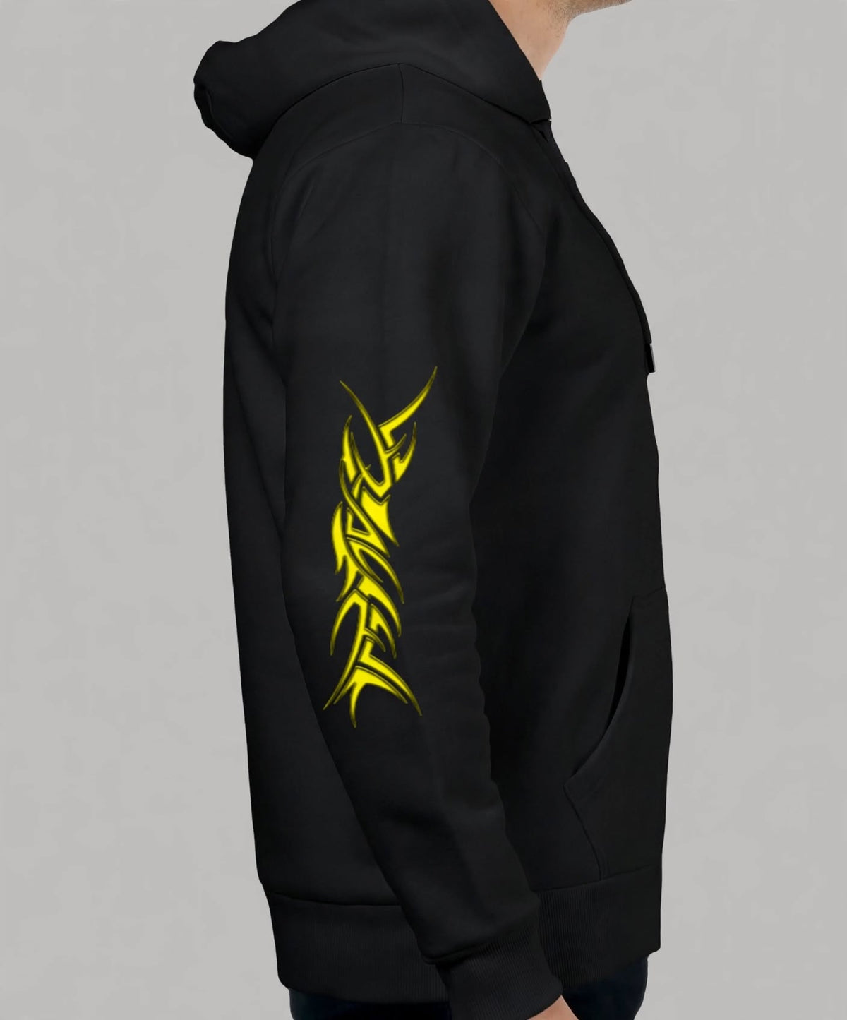 A black pullover hoodie shown on a model from the side, featuring a prominent yellow tribal graphic printed vertically down the left sleeve, against a solid grey background.