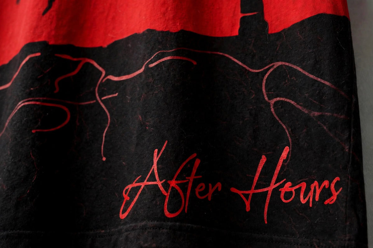 Close-up of a black graphic t-shirt featuring a red distressed top section with a silhouette design and the words 'After Hours' in red script.