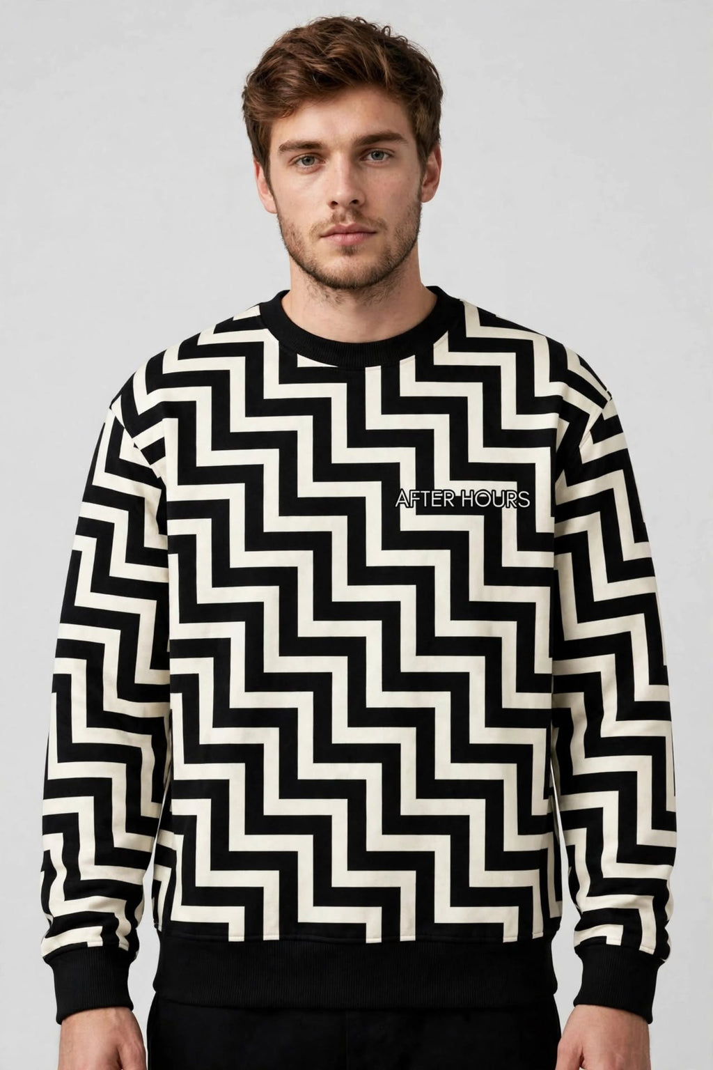 A man wearing a black and off-white zigzag patterned crewneck sweatshirt with 'AFTER Hours' printed on the chest, photographed against a neutral grey background.