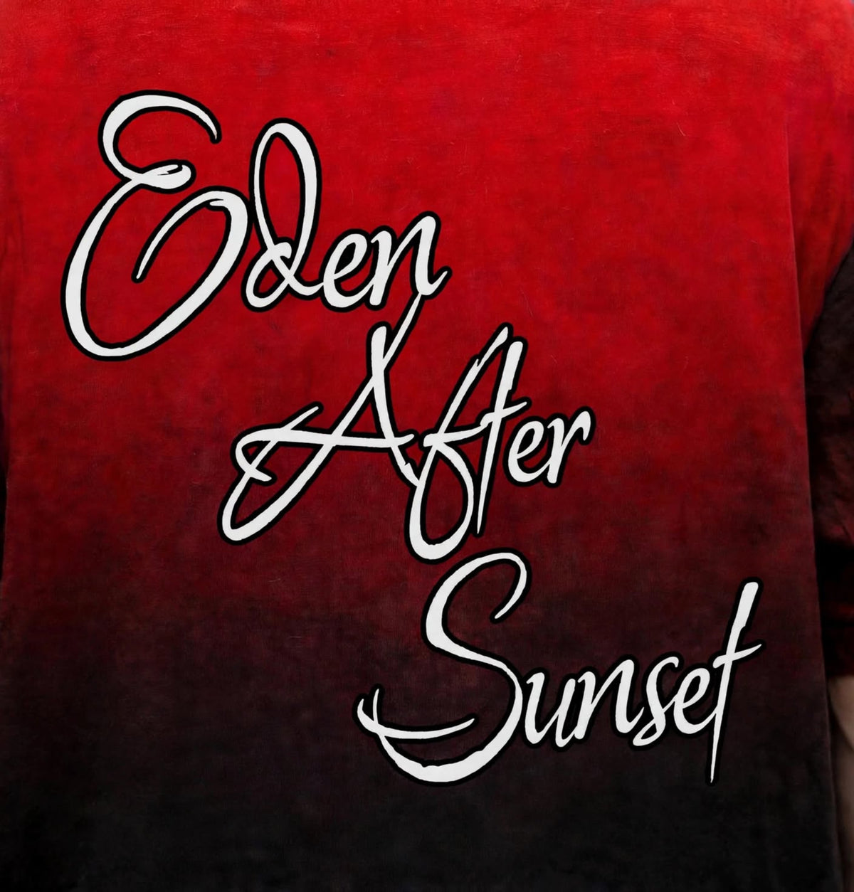 A close-up of a red and black gradient t-shirt featuring the phrase 'Eden After Sunset' printed in a white cursive script with a black outline.