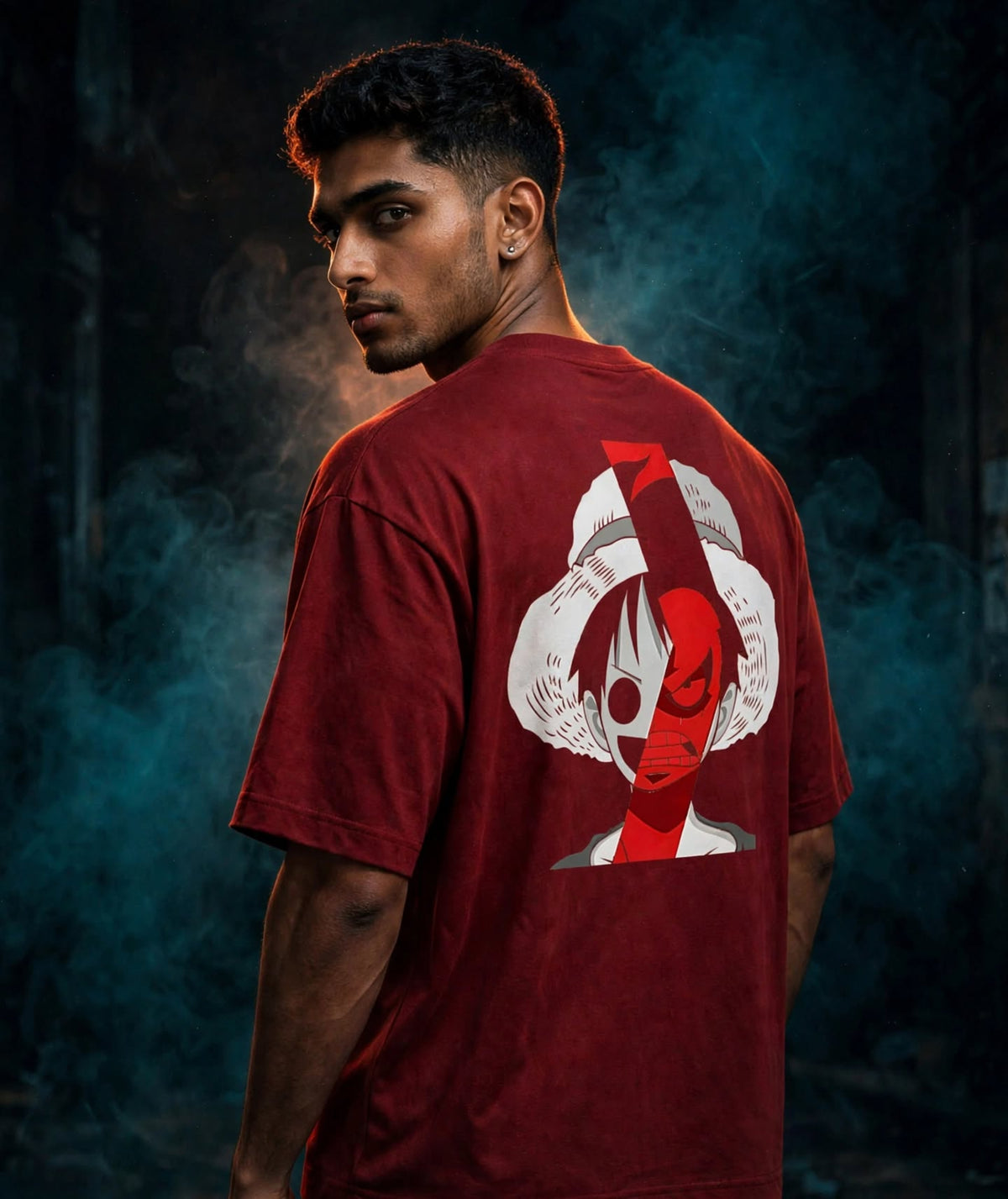 A man wearing a dark red t-shirt, shown from the back, featuring a large graphic print of a stylized character with red eyes. The background is dark and smoky with blue lighting.