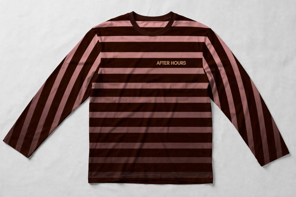A long-sleeve crewneck shirt with horizontal stripes in dark brown and dusty rose pink, featuring the text 'AFTER HOURS' printed in gold on the left chest, laid flat on a light grey textured background.